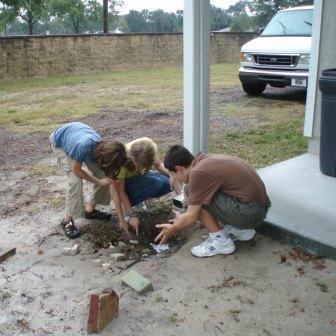 Students at Walden Community School in Florida look at water erosion from a gutter downspout at their school