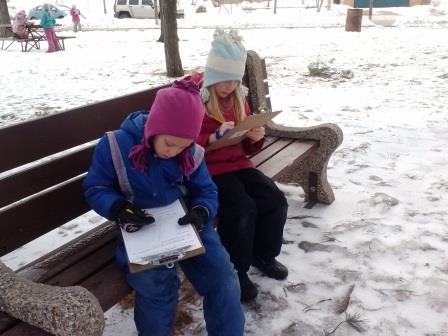 Students sitting on a bench in the snow record their observations of the outdoors