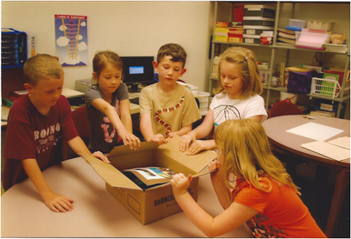 students-around-box-of-supplies-on-table