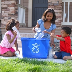 mother-and-children-put-items-in-blue-recycling-bin-at-home