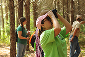 Girl in forest looks through binoculars 