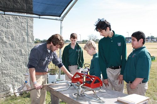 Students and their teacher at a school in Houston work on building a piece of equipment in the outdoors.