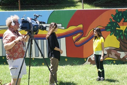 ABC Channel 7 film crew interview a student in front of school mural in Washington, DC.