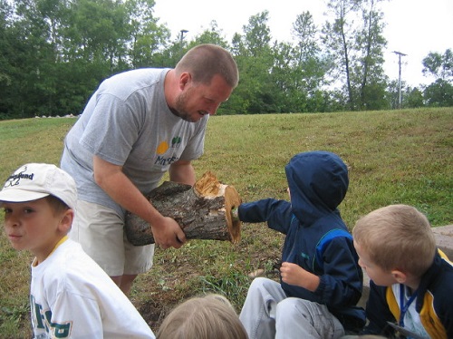 teacher-holds-log-for-young-boy-to-touch-and-examine