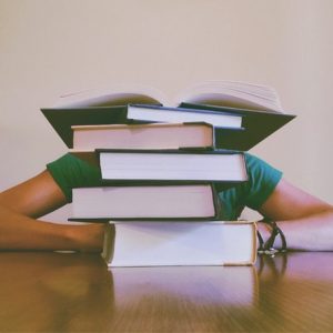 student behind a stack of books