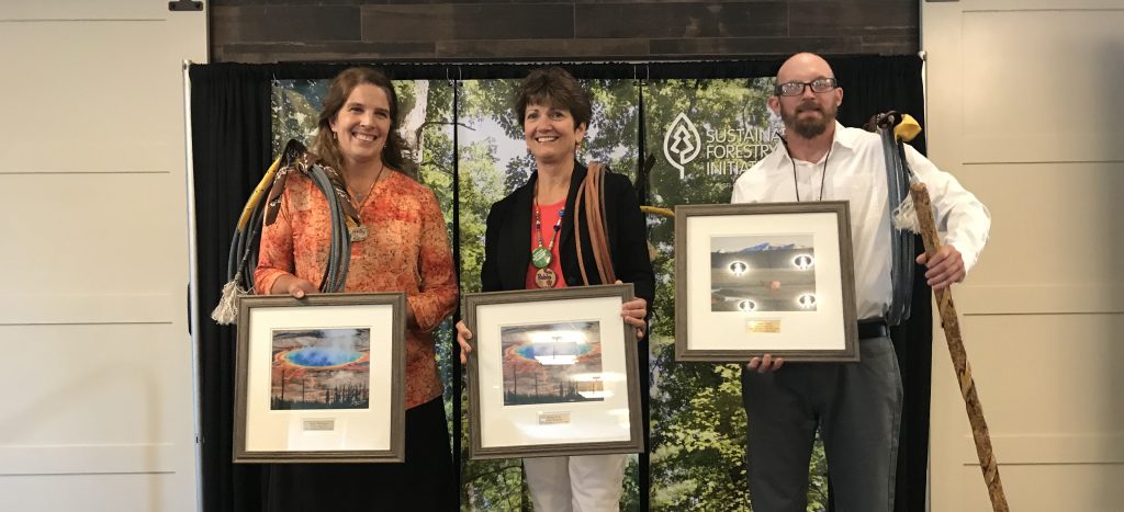 Three award winners standing with their certificate