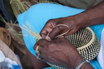 Hands weaving sweetgrass into beautiful baskets