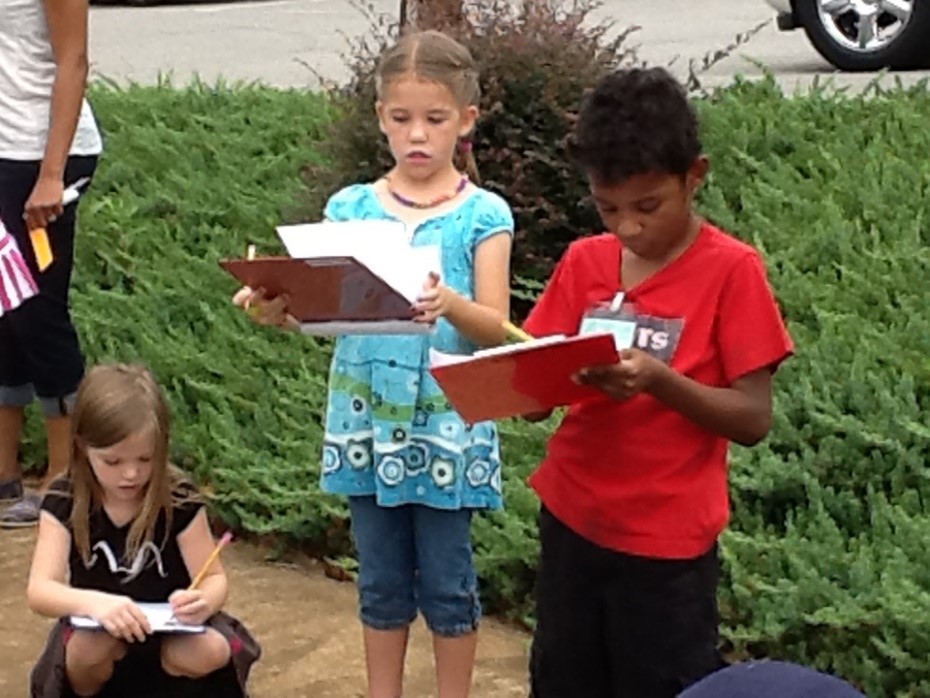 young-boy-girl-writing-clipboards-outdoors