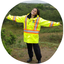 young woman with outstretched arms in a bright yellow safety jacket