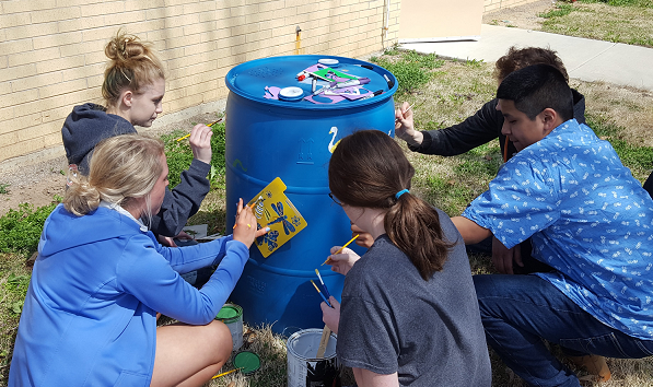 children decorate a rain barrel