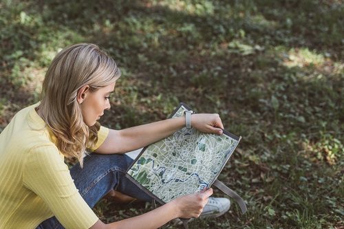 young woman sitting on ground outdoors looking at map