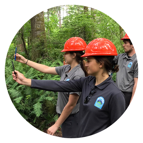 3 youth wearing red hard hats holding a measurement tool in front of them