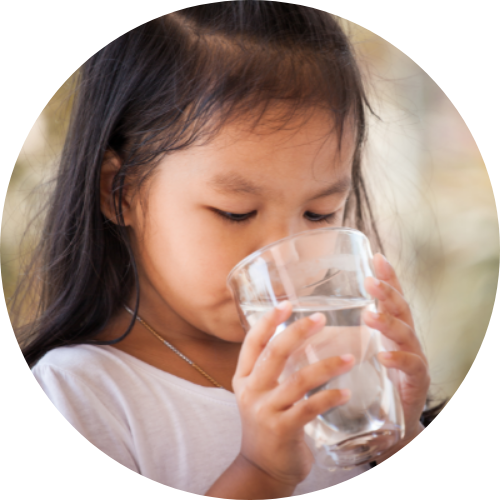 young girl holding a glass with two hands taking a sip of water