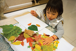 Young girl sitting at a desk with a pile of leaves