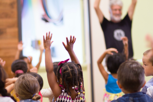 young children stretch out their arms and dance