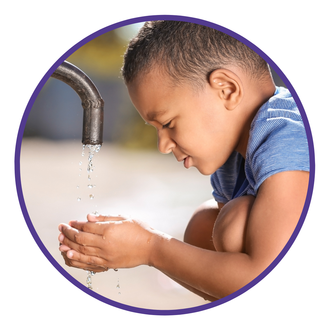 Young boy washing hands under a tap