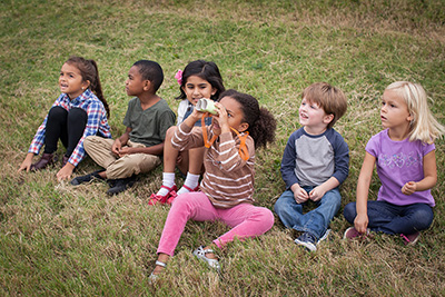 children sit on grass with crafted paper binoculars