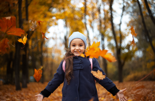 Young child walking through the vibrant orange woods during the fall